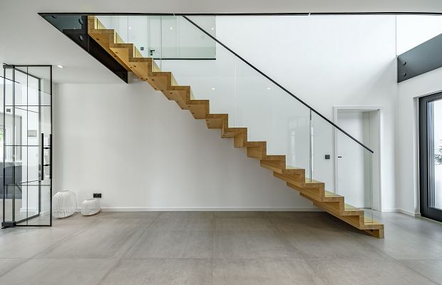 STREIF Innenraum Wohnbereich mit freitragender Holztreppe, Glasgeländer und minimalistischem Raumdesign