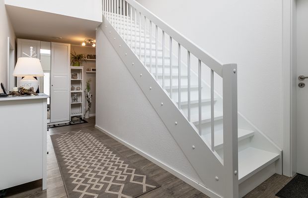 STREIF Innenraum Flur mit geradläufiger Treppe in Weiß, Geländer und Eingangsbereich mit Möbeln
