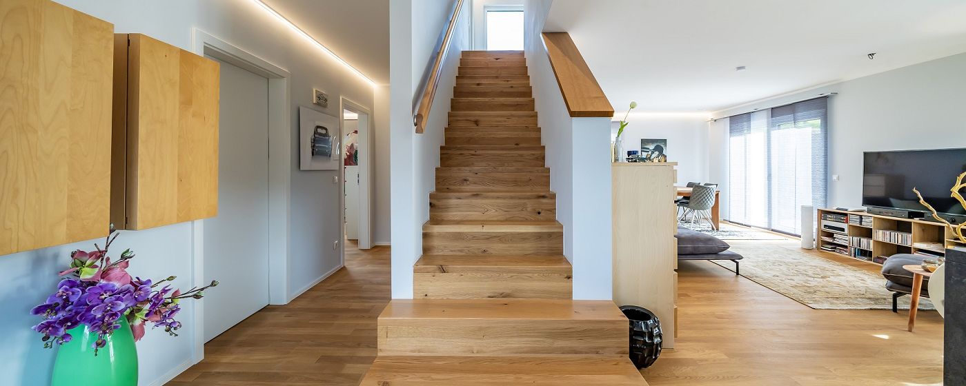 STREIF Innenraum Flur mit geradläufiger Holztreppe, offenen Wohnbereich und moderner Einrichtung