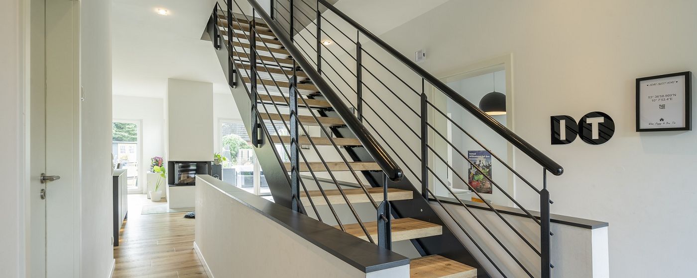 STREIF Innenraum Flur mit offener Treppe aus Holz und Metallgeländer, moderner Wohnbereich im Hintergrund
