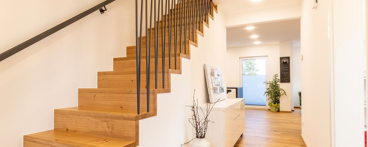 STREIF Innenraum Flur mit Holztreppe, vertikalem Geländer und hellem Wohnbereich im Hintergrund