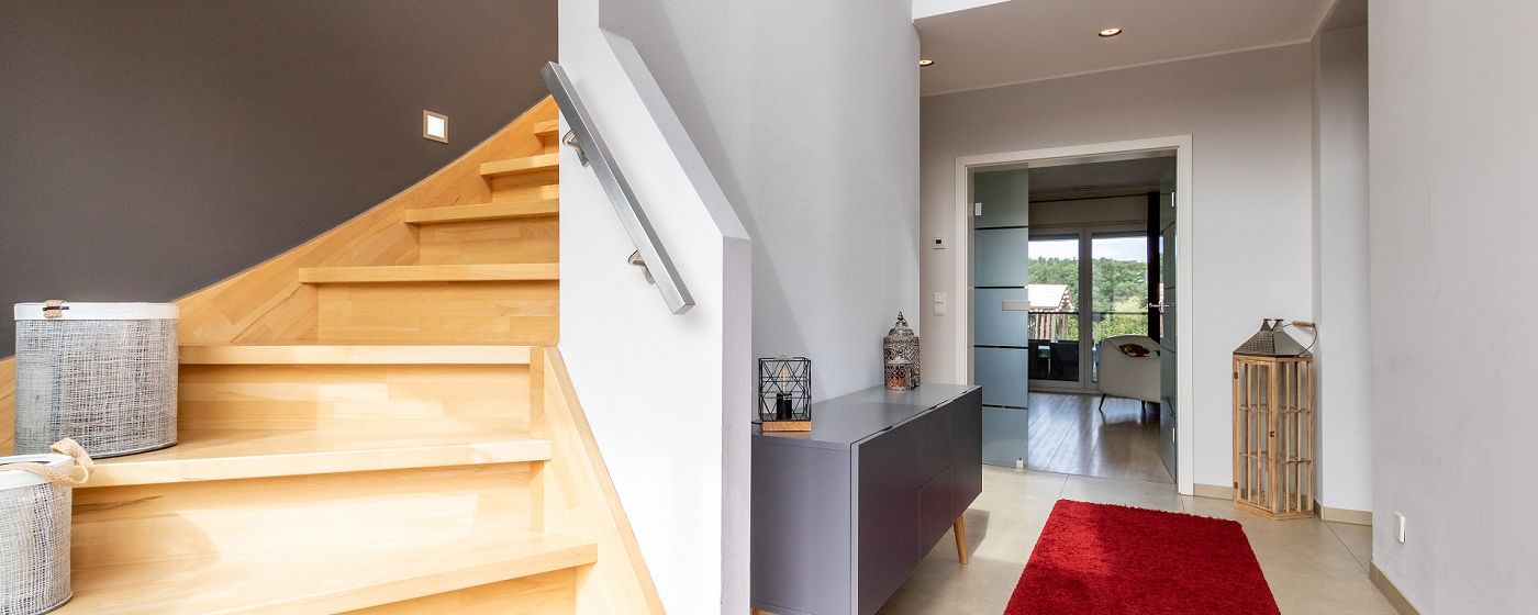 STREIF Innenraum Flur mit halbgewendelter Holztreppe, Sideboard und Durchgang zum Wohnbereich in moderner Gestaltung