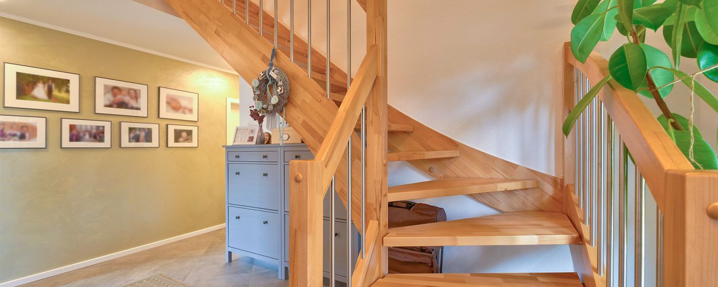 STREIF Innenraum Flur mit viertelgewendelter Holztreppe, Kommode und dekorativer Wandgestaltung