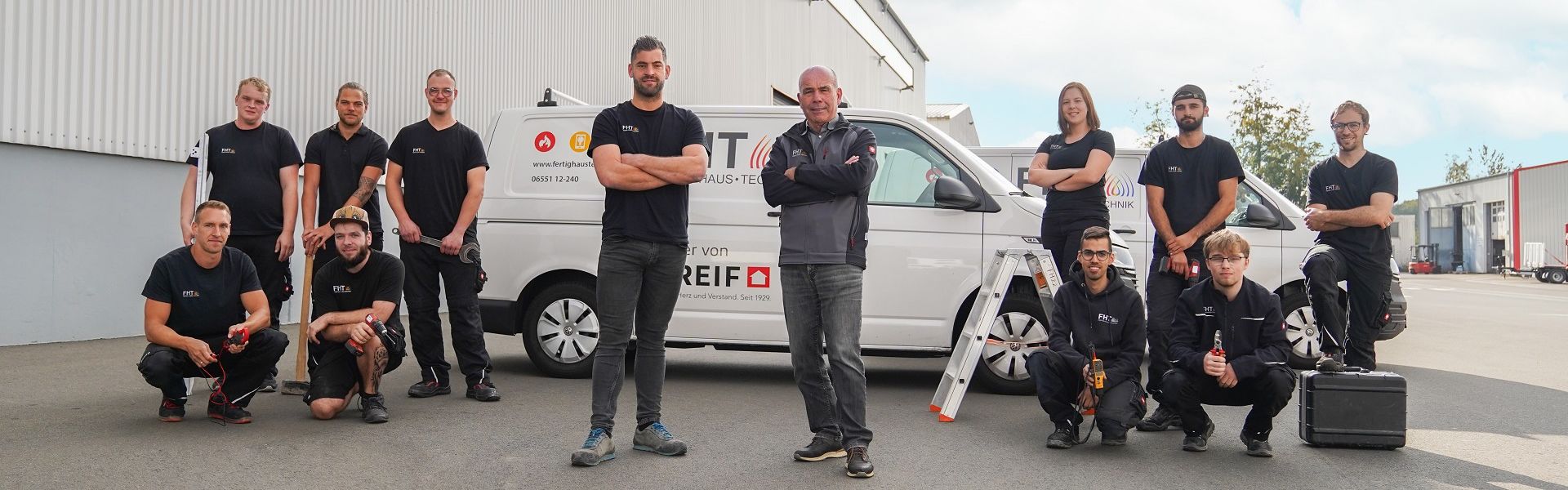 Mitarbeiter Team Servicegruppe vor Firmenfahrzeug mit Werkzeugen, Gruppenaufnahme im Außenbereich vor Betriebsgebäude
