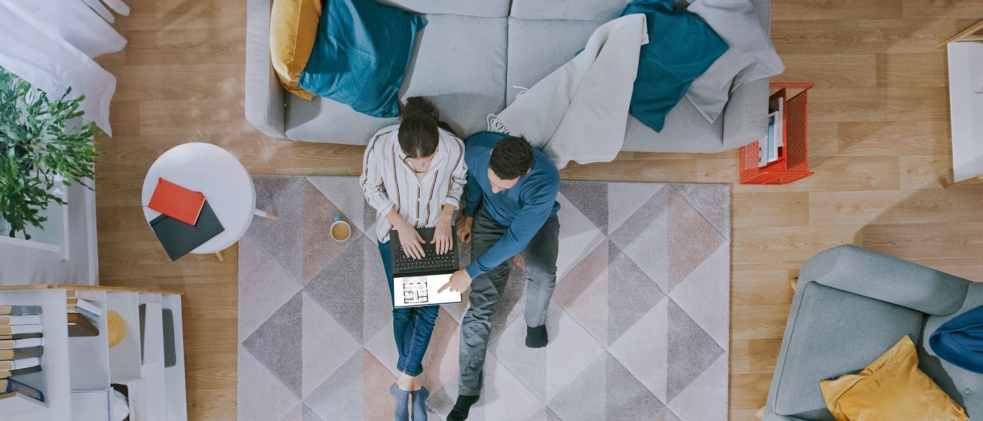 Wohnsituation Paar plant Fertighaus im Wohnzimmer mit digitalem Grundriss aus Vogelperspektive
