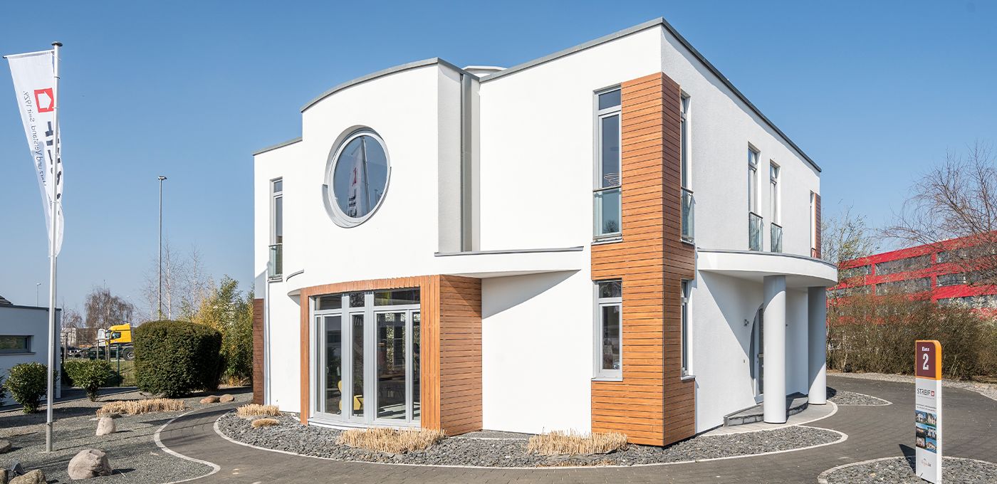 Fertighaus Stadtvilla zweigeschossig mit Flachdach, weißer Putzfassade, Holzakzenten, Rundfenster und Einfahrt