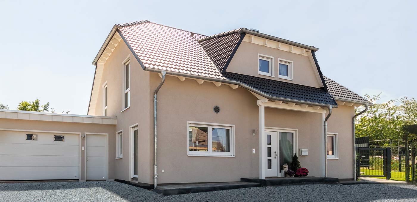 Fertighaus Einfamilienhaus zweigeschossig mit Satteldach, heller Putzfassade, Garage und Einfahrt