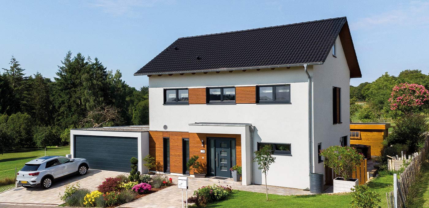 Fertighaus Einfamilienhaus zweigeschossig mit Satteldach, weißer Putzfassade, Garage, Einfahrt und Garten