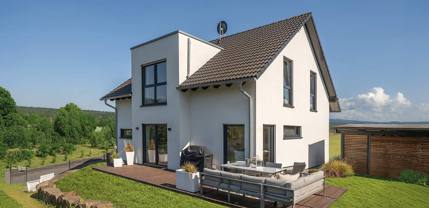 Fertighaus Stadtvilla zweigeschossig mit Satteldach, weißer Putzfassade, Terrasse, Carport und Hanglage