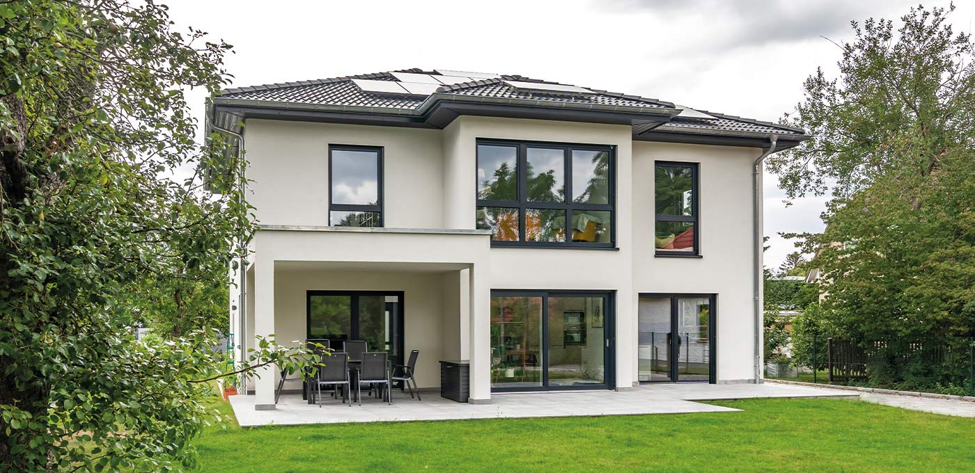 Fertighaus Stadtvilla zweigeschossig mit Walmdach, heller Putzfassade, Terrasse und Garten